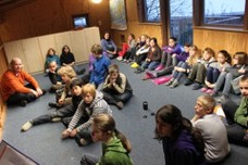 Schüler und der Lehrer sitzen in einem Klassenraum auf dem Boden