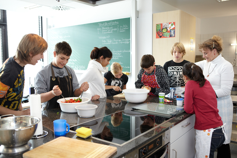 Lehrerin, Schülerinnen und Schüler beim Kochen