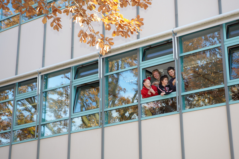 Schülerinnen und Schüler schauen aus einem Fenster