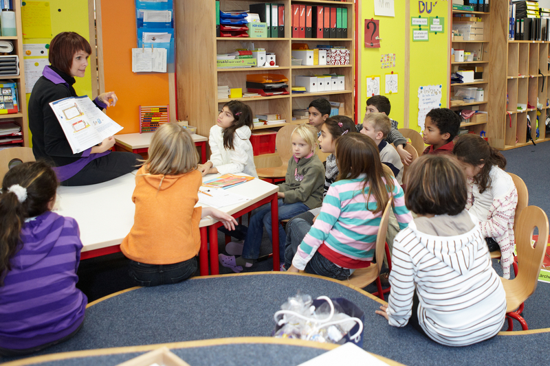 Lehrerin mit Schülerinnen und Schülern im Unterricht