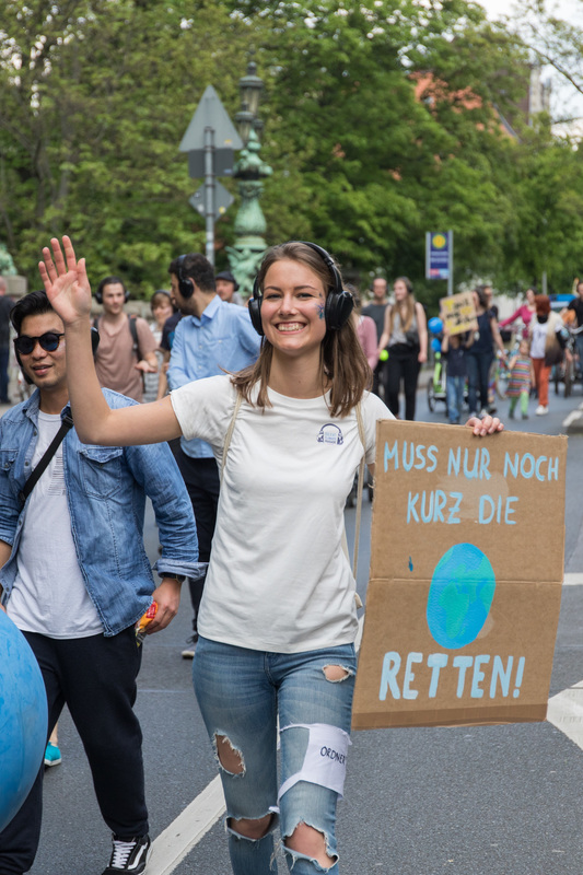 Demnonstrantin mit einem "Muss kurz noch die Welt retten"-Schild