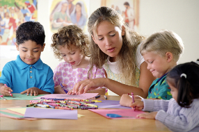 Eine Lehrerin mit kleinen Kindern beim Malen.