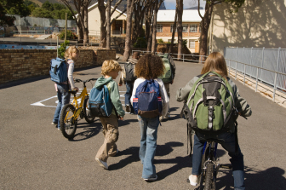 Schulkinder mit Schulrucksäcken auf dem Schulweg.