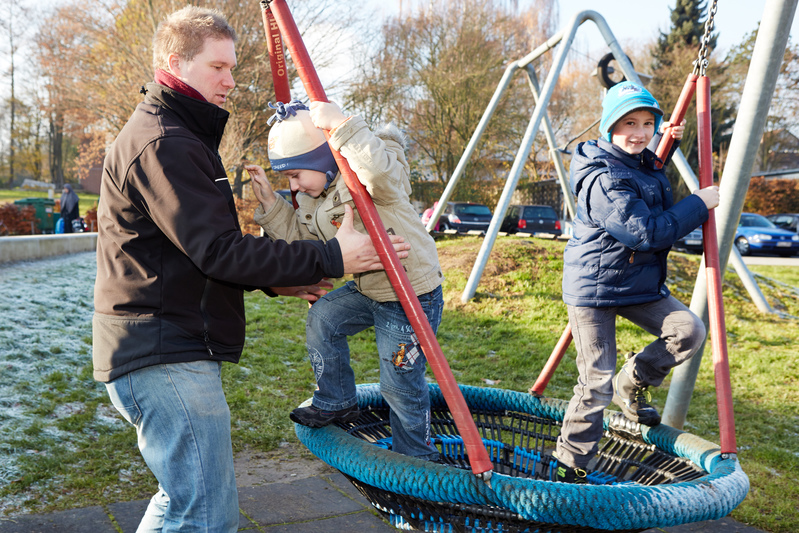 Vater mit Kindern auf einer Schaukel