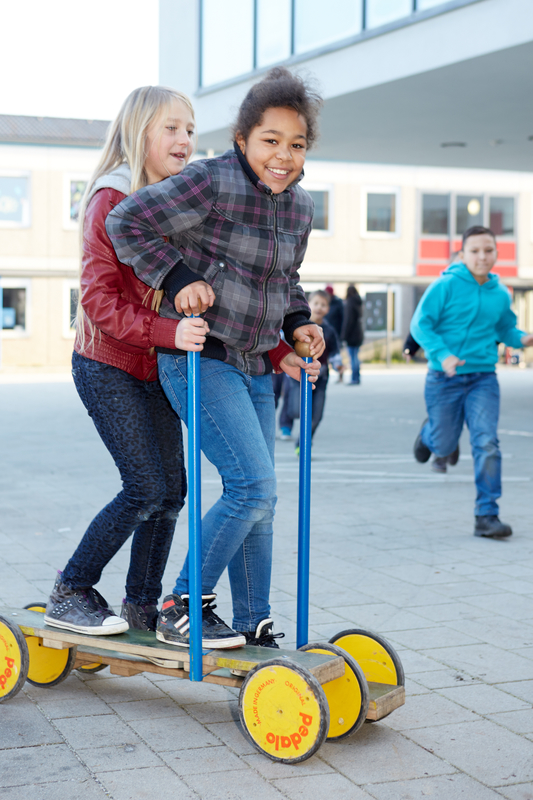 Schülerinnen mit einem Sportgerät auf dem Schulhof