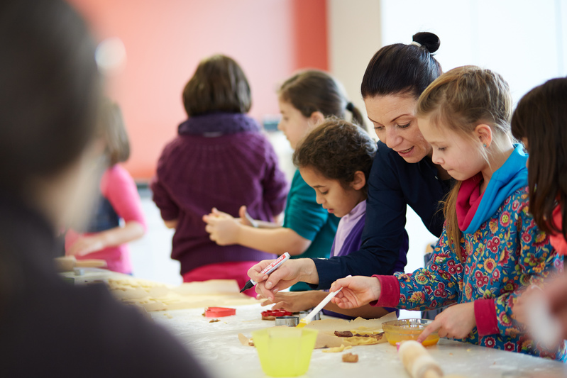 Erzieherin mit Schülerinnen und Schülern beim Backen