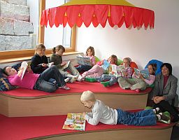 Kinder sitzen oder liegen auf verschiedenen Podesten und lesen