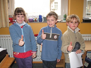 Drei Kinder halten den hochgestreckten Daumen in die Kamera.