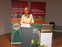 Eine Frau steht an einem Rednerpult und spricht.