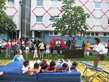 Kinder bei einer Vorführung auf Gymnastikmatten und einem Trampolin.