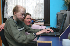 Ein Junge erhält von einer Lehrerin Unterricht am Computer
