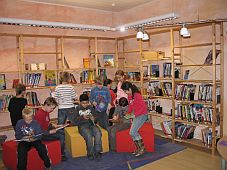 Kinder sitzen lesend in einem Raum voller Bücherregale