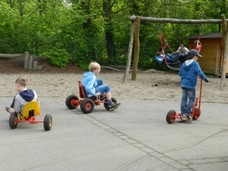 Schüler auf Dreirädern und Rollern im Schulhof