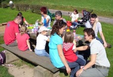 Schüler, Eltern und Lehrer auf einem Grillplatz im Grünen