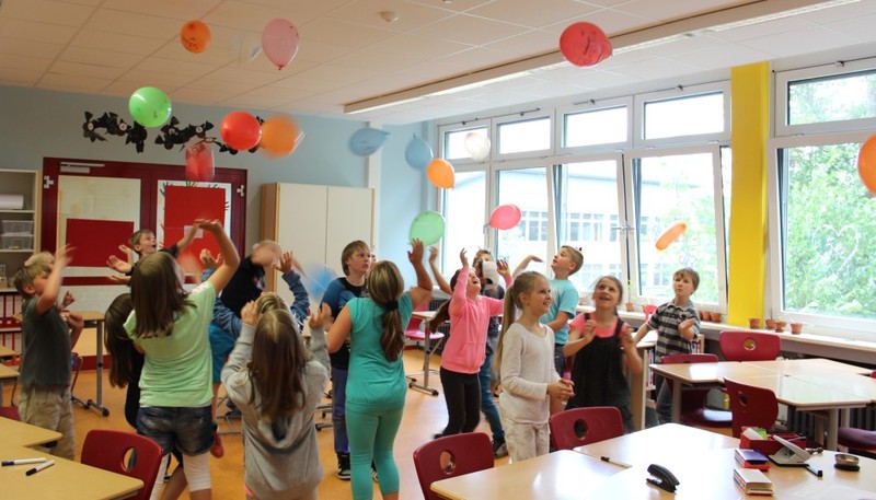 Schülerinnen und Schüler mit Luftballons im Klassenraum