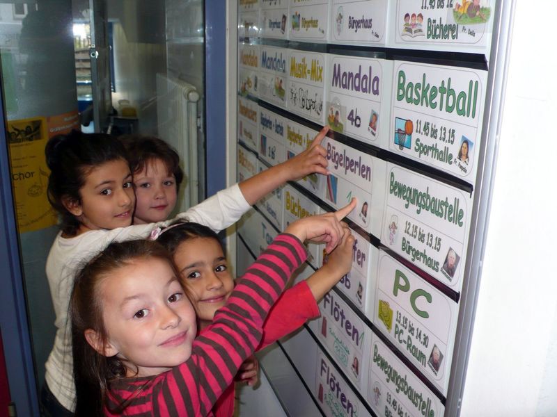 Schülerinnen und Schüler vor einer Tafel mit den Angeboten fürs Mittagsband