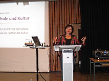 Eine Frau steht an einem Rednerpult und spricht.