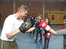 Ein Lehrer gibt Mädchen Boxunterricht in einer Sporthalle.
