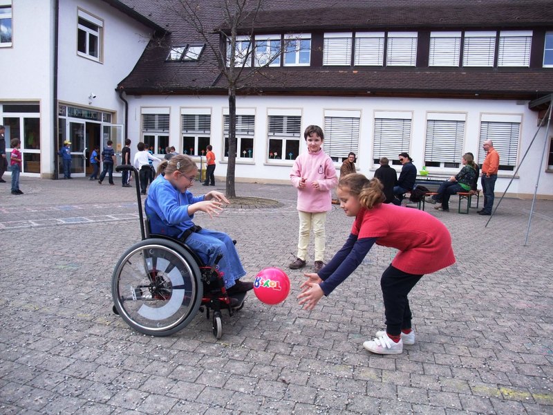 Schülerinnen, davon eine im Rollstuhl, spielen Ball