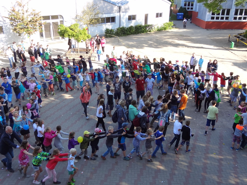 Schülerinnen und Schüler machen auf dem Schulhof eine Polonaise