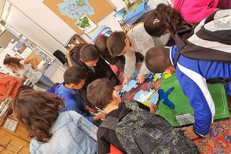 Schülerinnen und Schüler beugen sich über ein Riesen-Puzzle