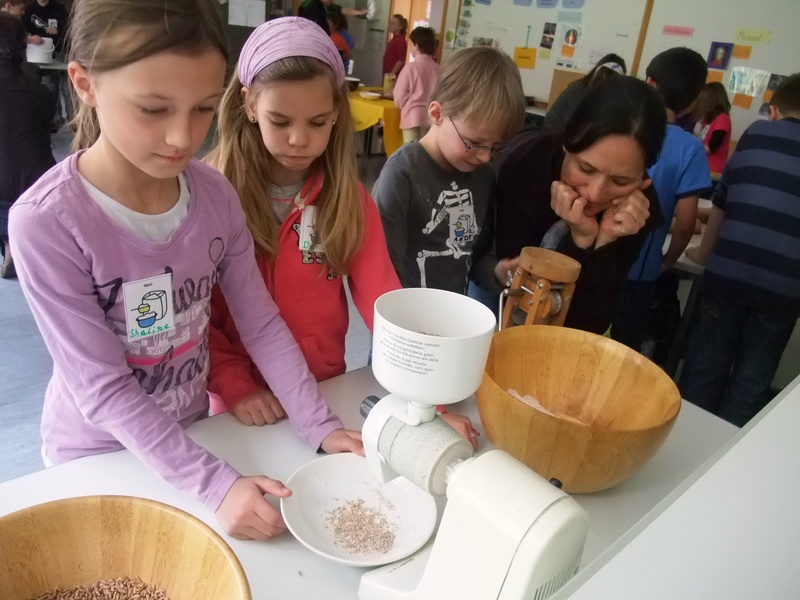 Schülerinnen und Schüler beim Mahlen von Getreide