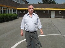 Ein Mann steht vor einem Schulgebäude.