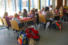 Blick in eine Schulmensa mit essenden Kindern.