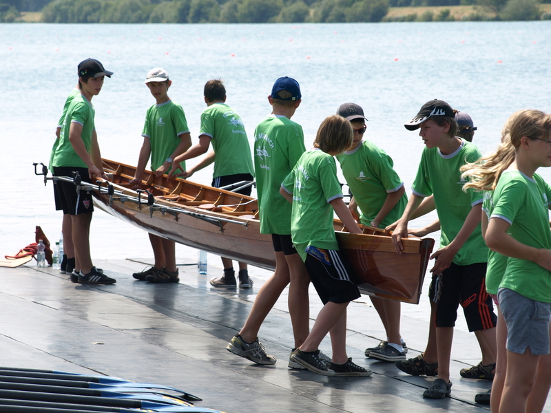 Schülerinnen und Schüler tragen Ruderboot