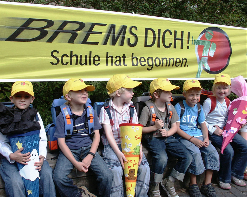 Erstklässer sitzen vor einem Banner "Brems Dich!"