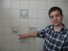 Schüler zeigt auf eine bemalte Fliese