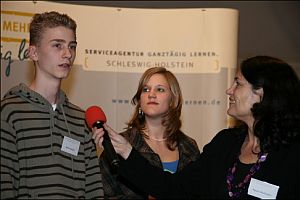 Ein schüler und eine Schülerin werden von einer Frau interviewt