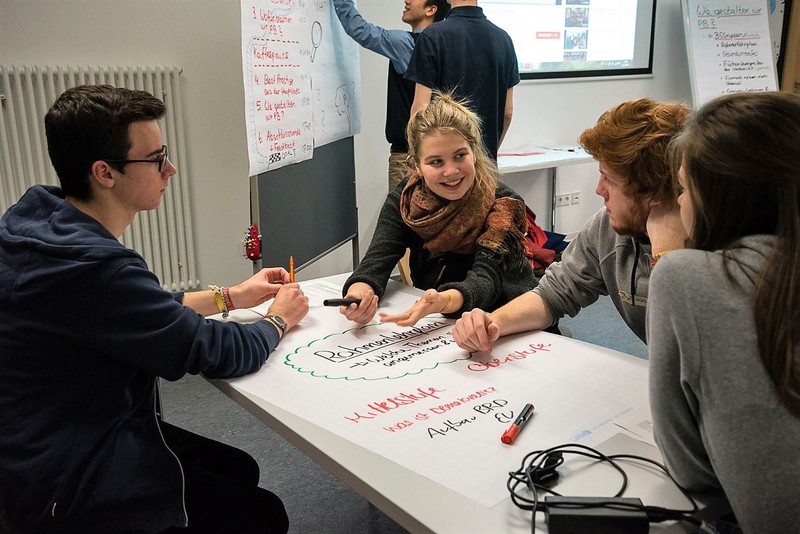 Schülerinnen und Schüler tauschen sich an einem Tisch aus