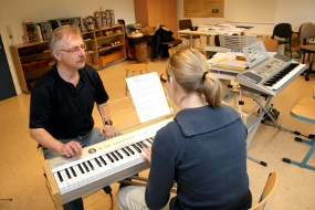 Lehrer und Schüler beim Unterricht am Keyboard.
