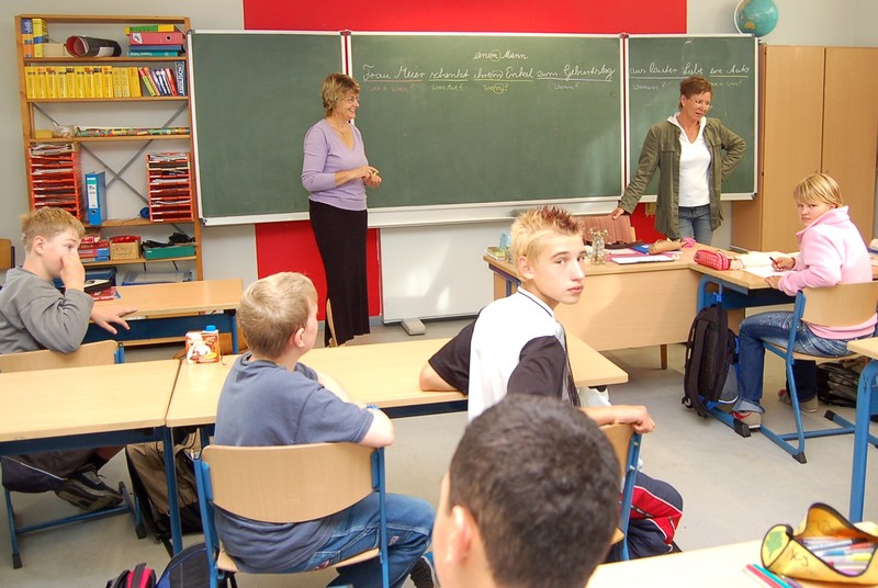Unterricht: Zwei Lehrerinnen an der Tafel vor der Klasse