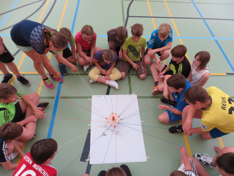 Schülerinnen und Schüler im Kreis bei einem Kooperationsspiel